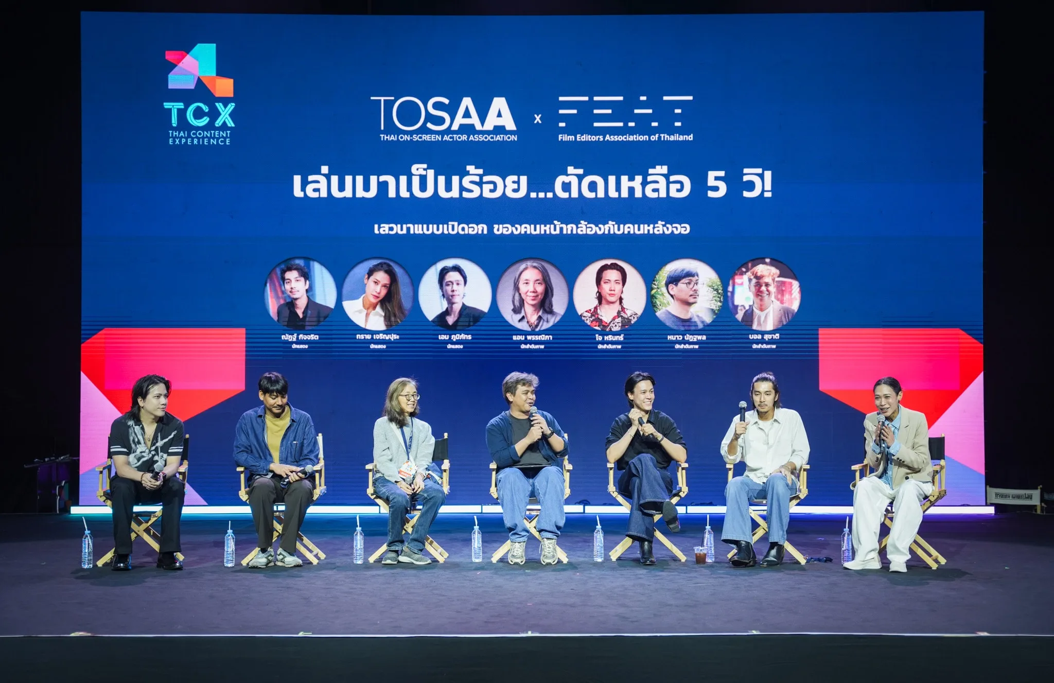 ผู้ร่วมเสวนานั่งเรียงกันบนเวทีพร้อมฉากหลังแนะนำวิทยากร